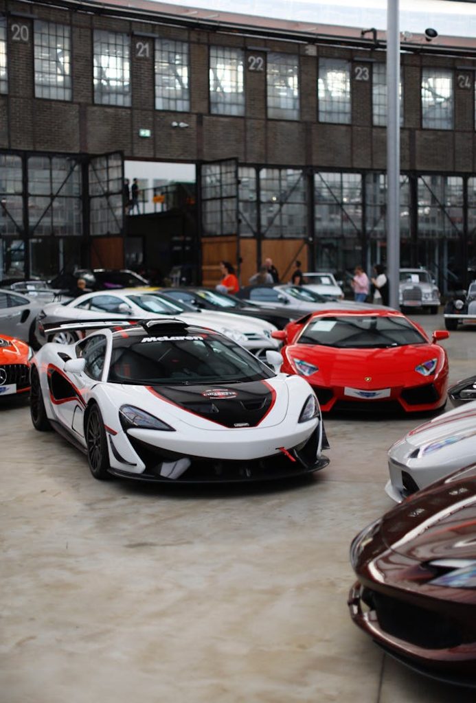 a-group-of-sports-cars-parked-in-front-of-a-building-27591714 Luxury sports cars displayed in an industrial-style showroom with onlookers.